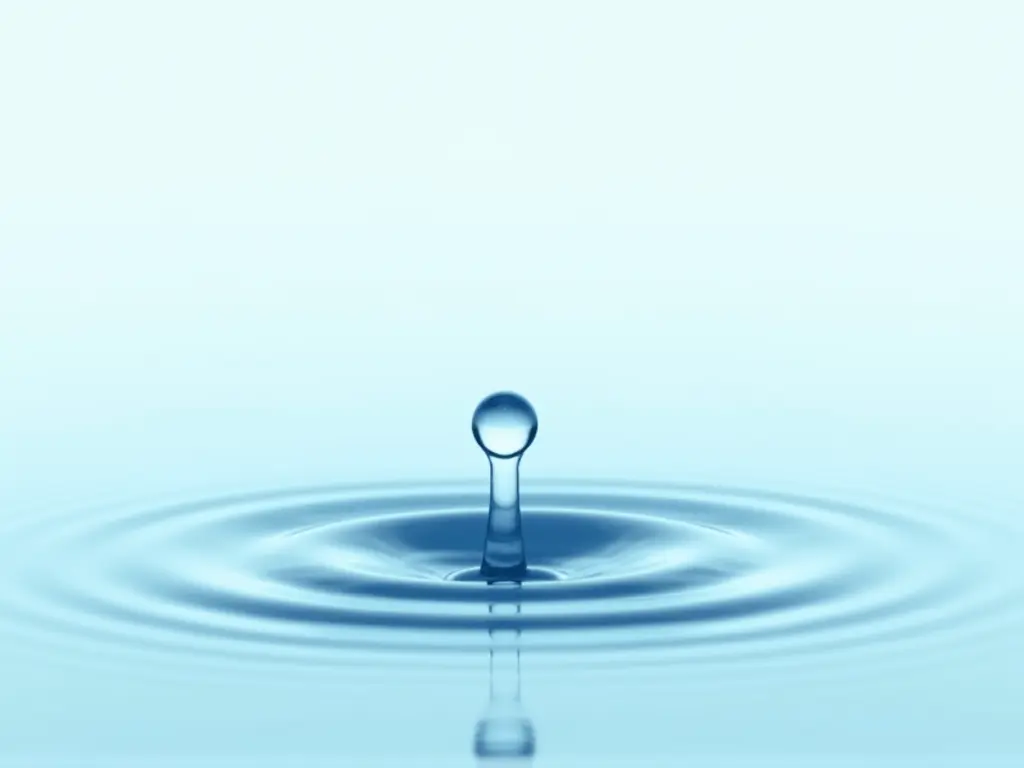 A single droplet of water hitting a still surface, creating ripples expanding outward, symbolizing the influence of mindset.